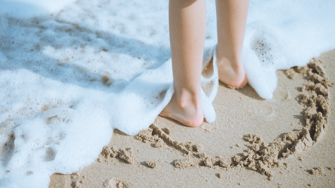 Feet stand in water on the beach.